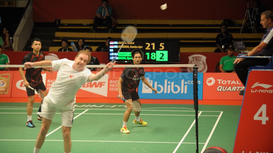 Mathew Fogarty yang telah berusia 58 tahun berusaha mengembalikan shuttlecock dari Andrei/Hendra.